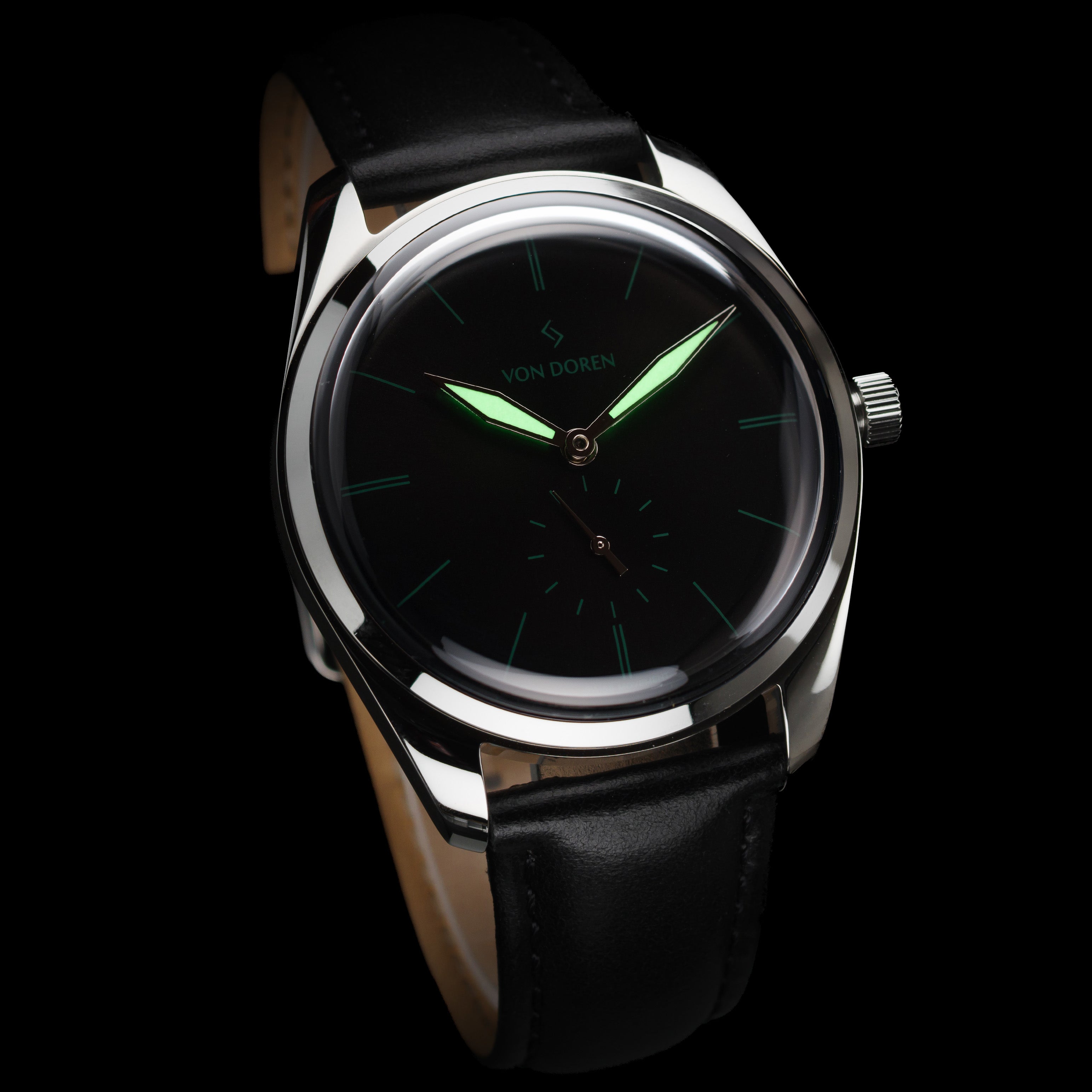 Von Doren-klokke med sort tallskive, selvlysende grønne visere og sort lærrem mot mørk bakgrunn.