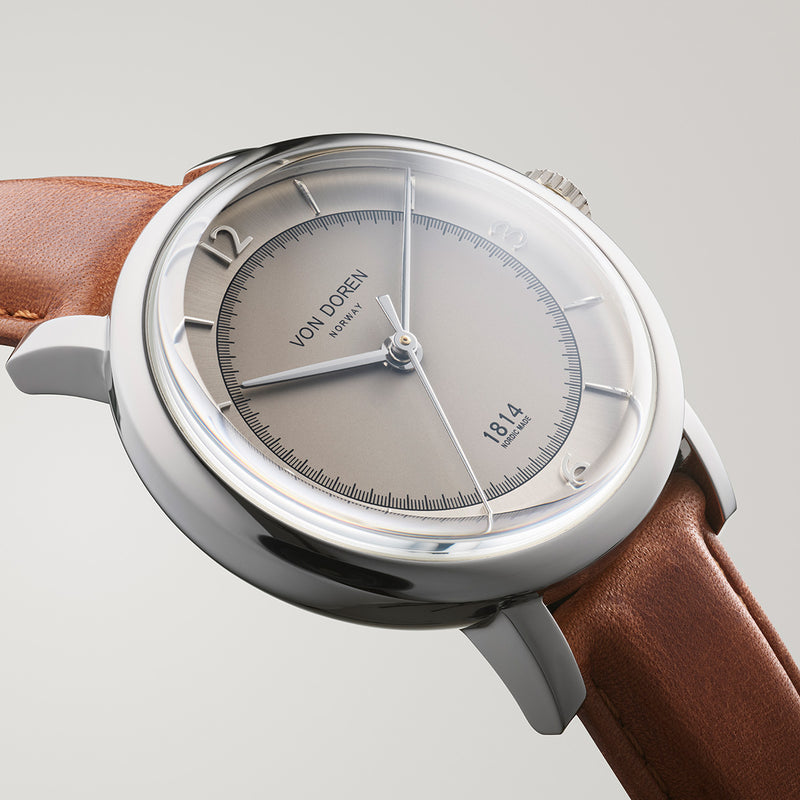 Close-up of the Von Doren 1814 with domed sapphire crystal, silver dial and brown leather strap in polished steel case.