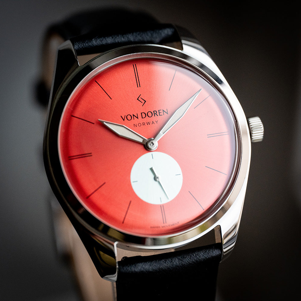 Runde Chili ett skrått forfra. Chili farget skive og sort skinnreim.