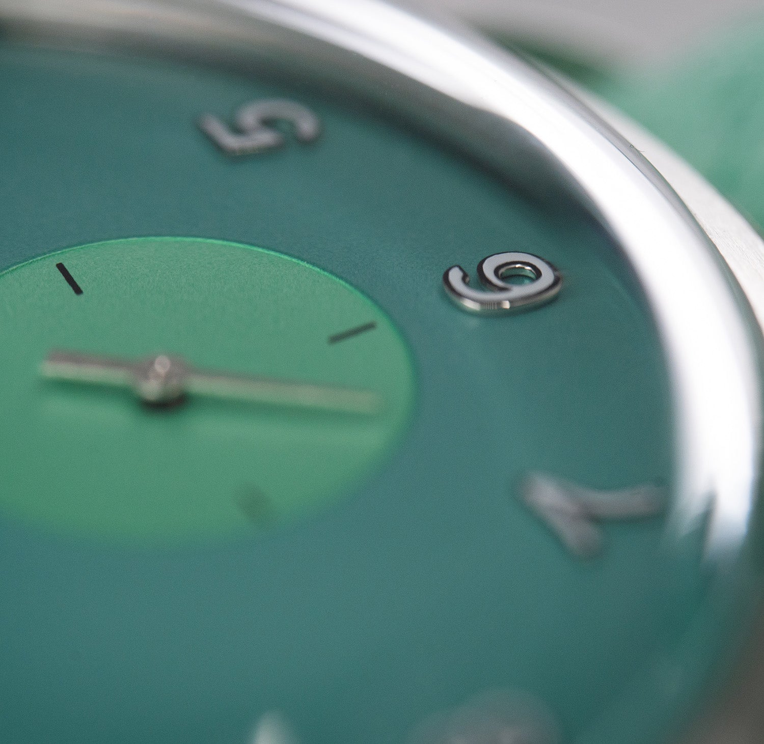 Makrobilde av Von Doren Runde Candy Mint-klokke med grønn tallskive og sølvfargede opphøyde tall, fokusert på subdialen ved klokken seks.
