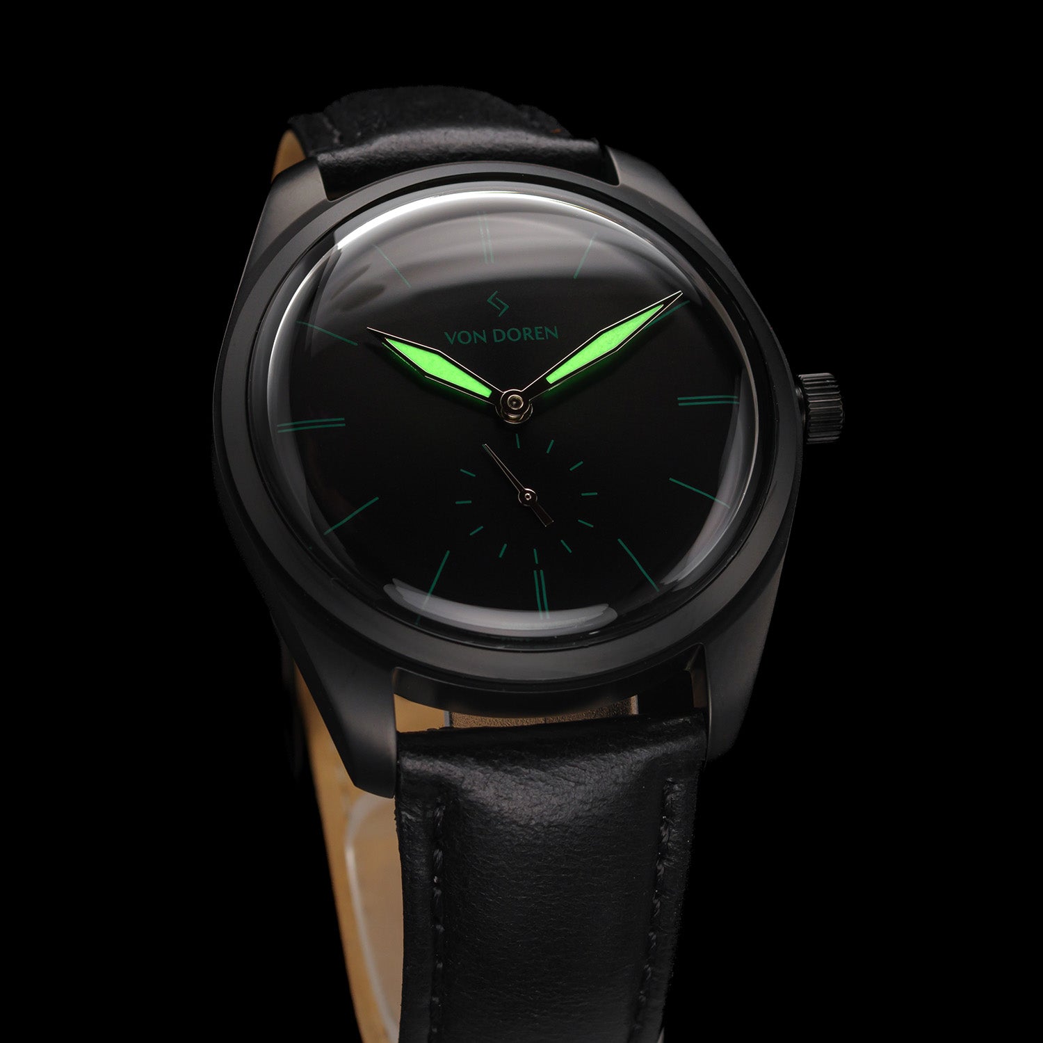 Klokke i sort stål med sort skive g sort skinnreim. Selvlysende visere. 