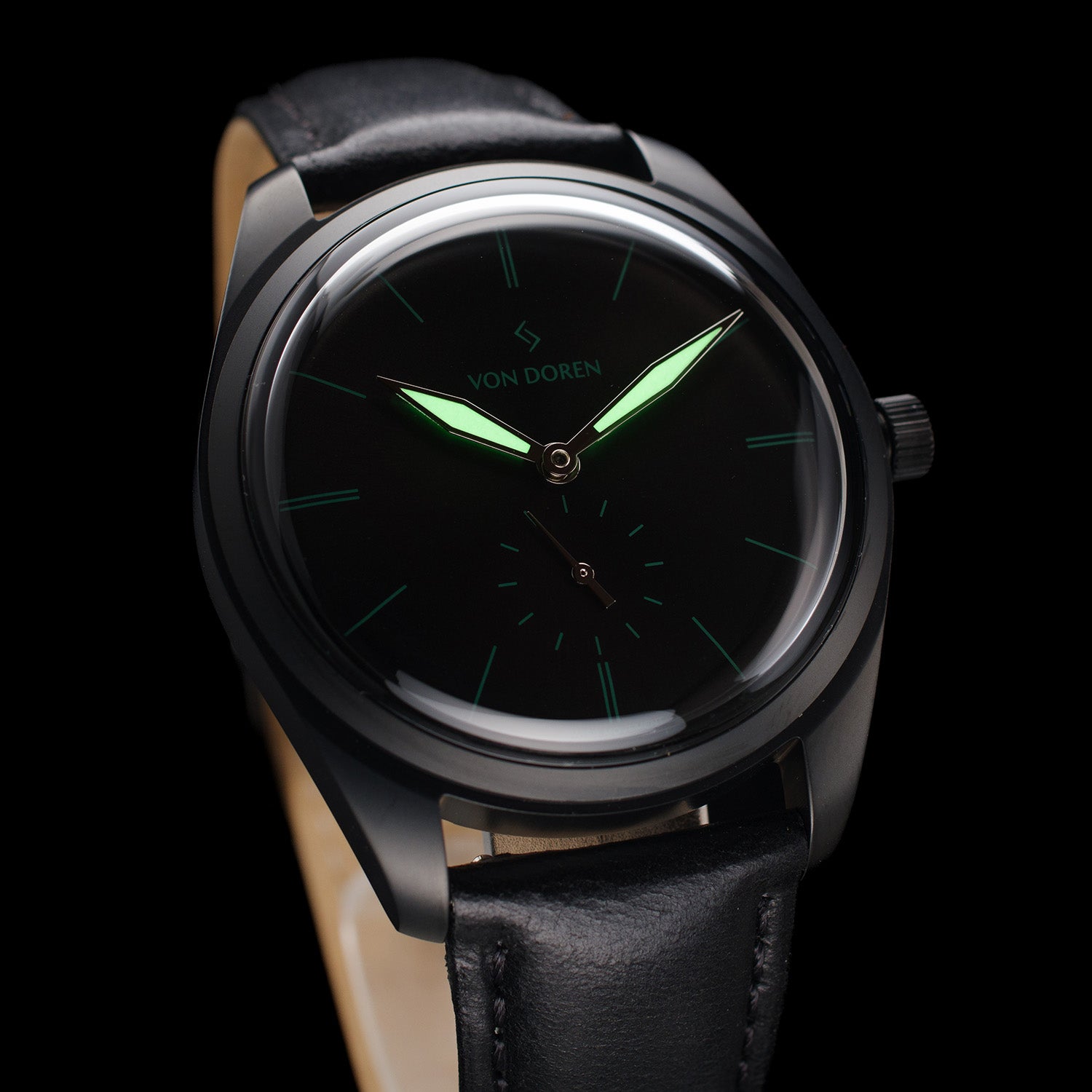 Armbåndsur i sort stål, med sort skive og sort rei. Viserene lyser i mørket.