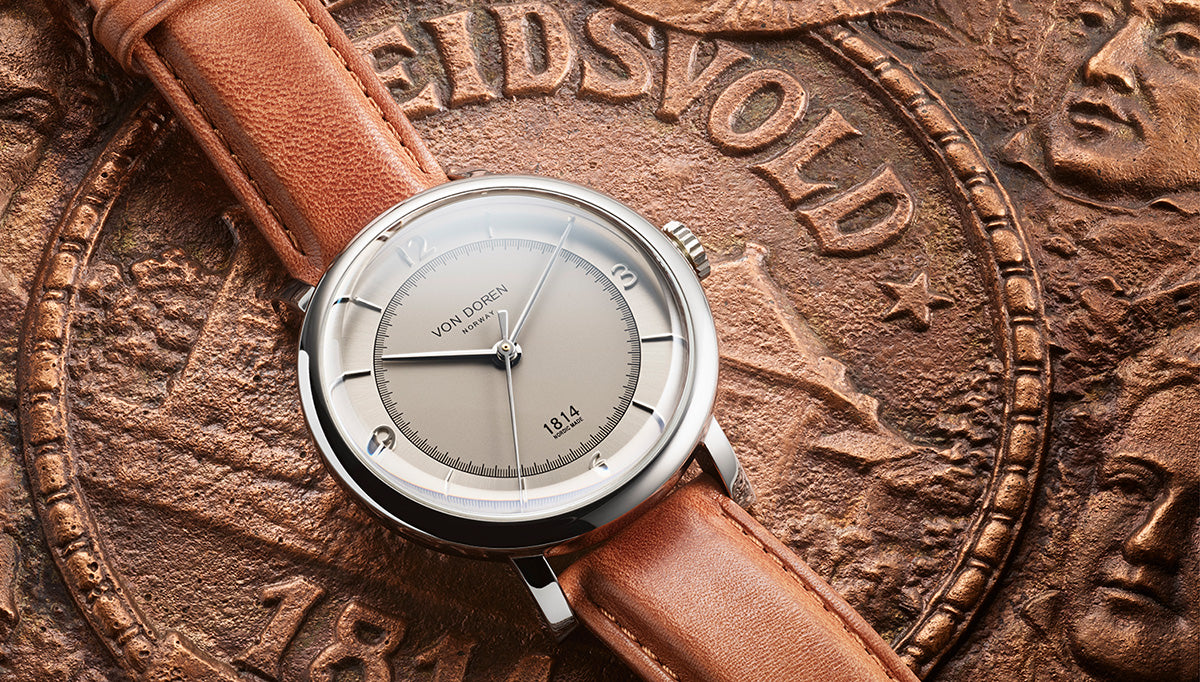 Von Doren 1814 with light dial and brown leather strap resting on a historic Eidsvoll medallion inspired by Norway’s Constitution.
